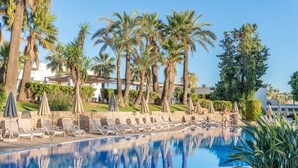 A pool with lounge chairs and umbrellas, surrounded by palm trees and greenery. - Welikehotel Marfil Playa (Sa Coma)