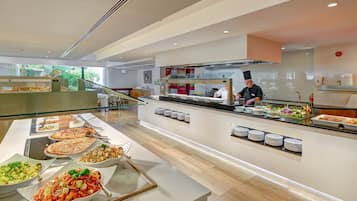 Zona de buffet con diversas opciones de comida, un chef preparando alimentos y una decoración interior moderna.