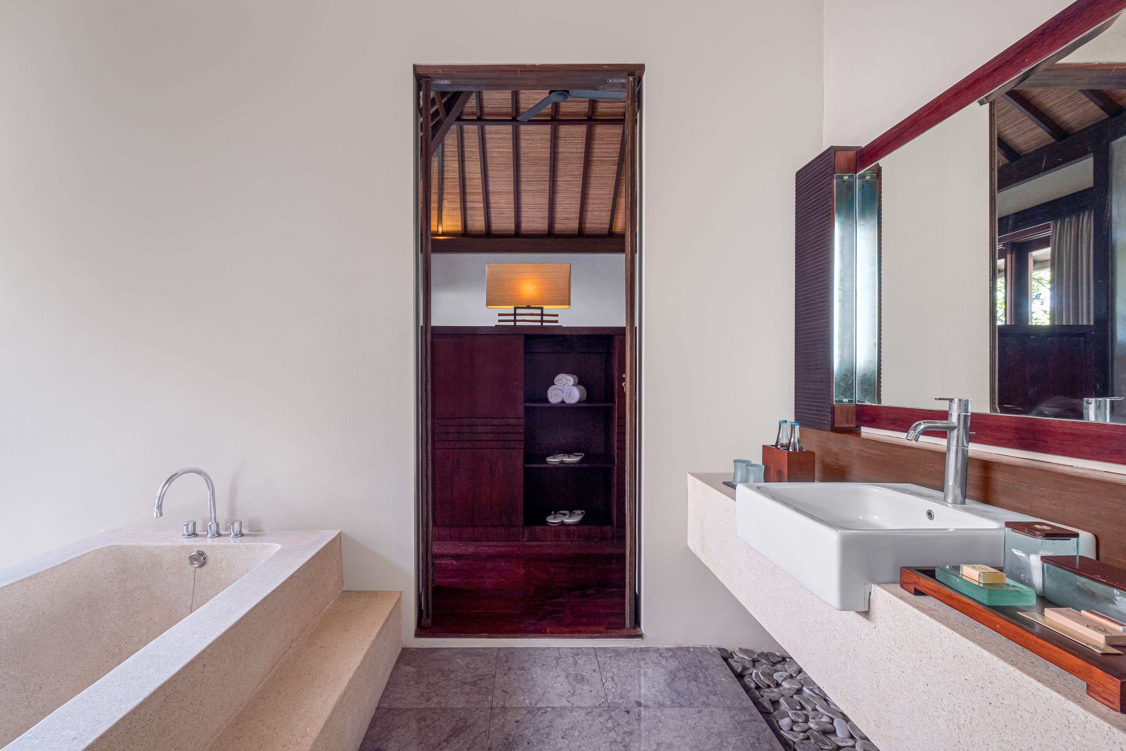 A modern bathroom with a bathtub, a vanity with a mirror, and a built-in shoe rack.