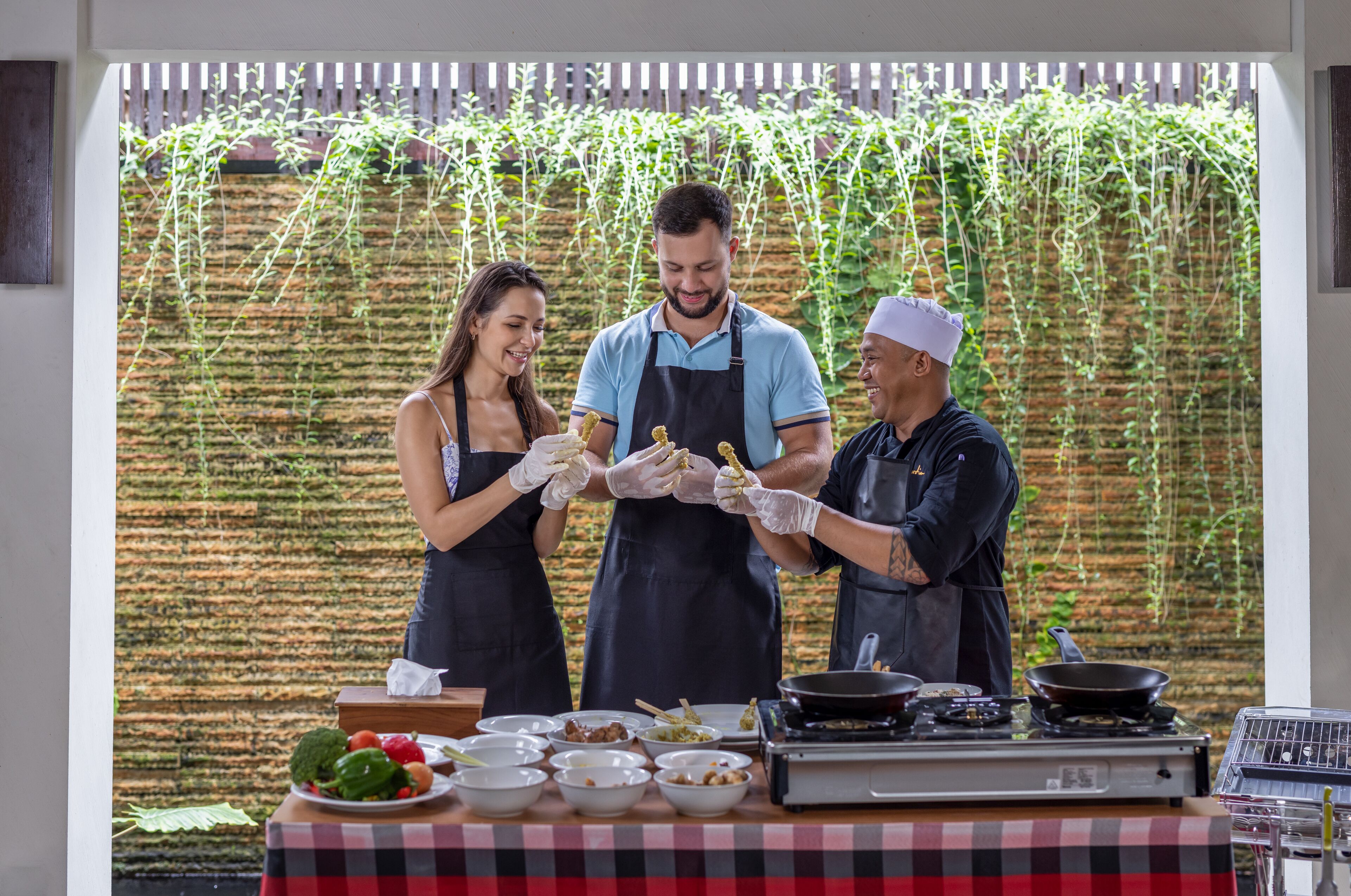 A chef preparing food outdoors with a table of ingredients and cooking utensils.