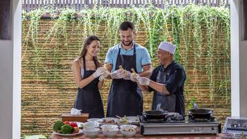 A chef preparing food outdoors with a table of ingredients and cooking utensils.