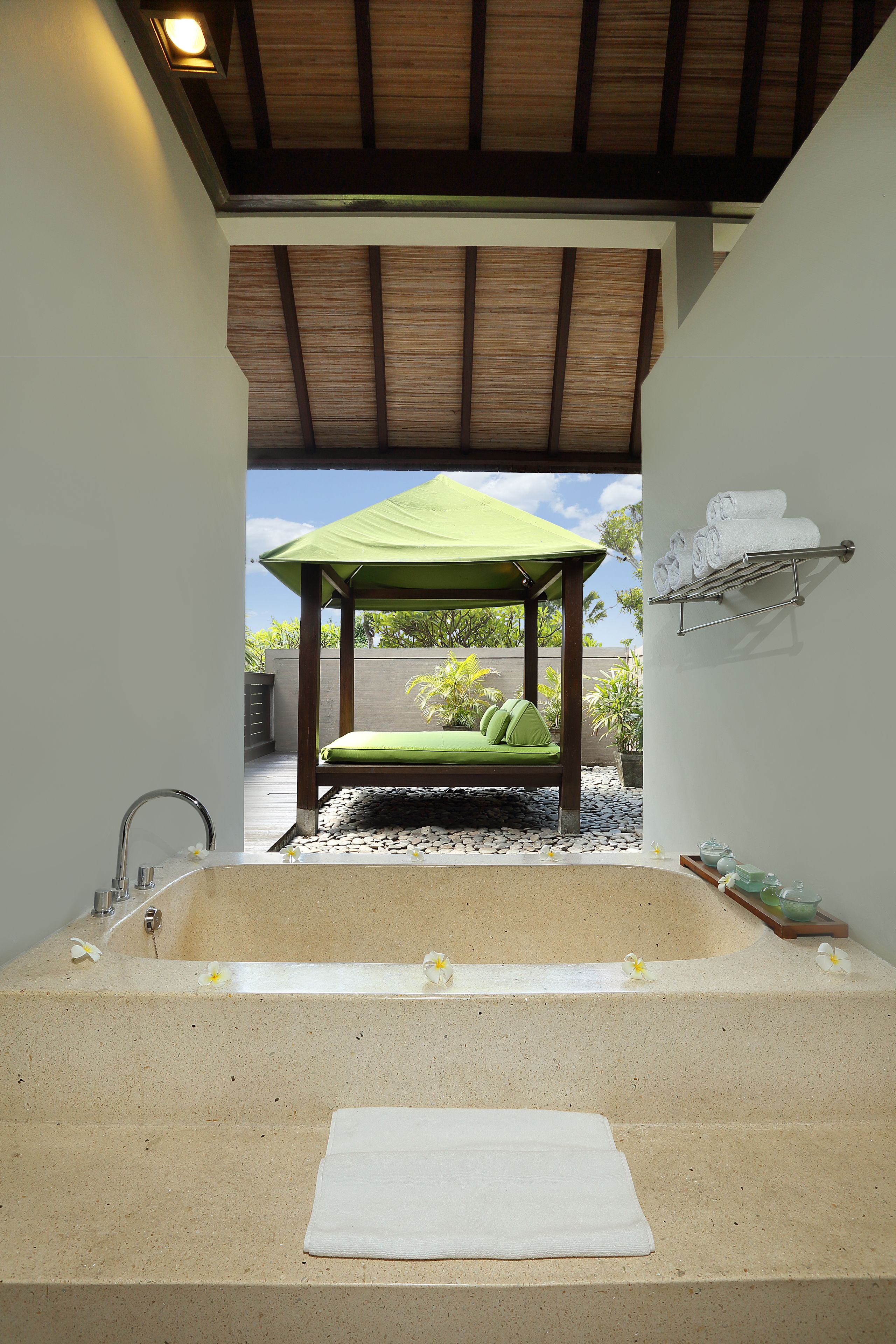 A spa area with a large bathtub, a green canopy, and a towel rack.