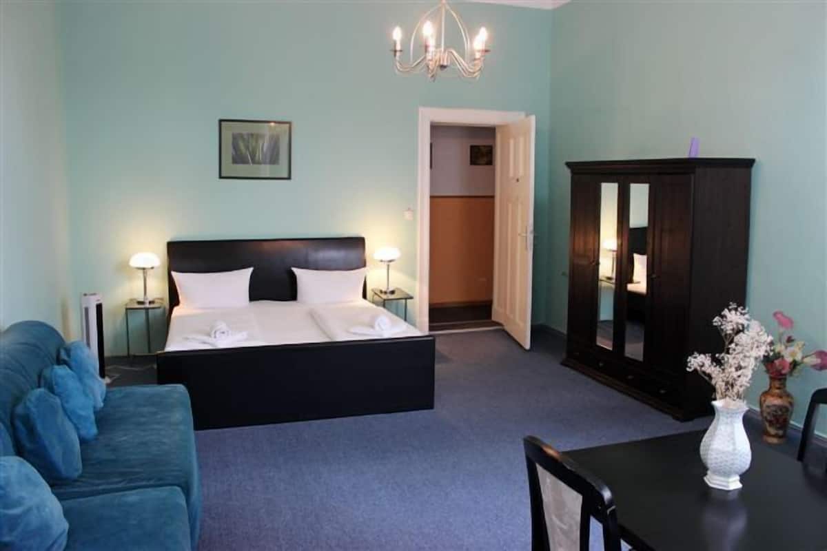 Une chambre à coucher avec un lit, des tables de chevet, une commode, une chaise et un vase avec des fleurs.