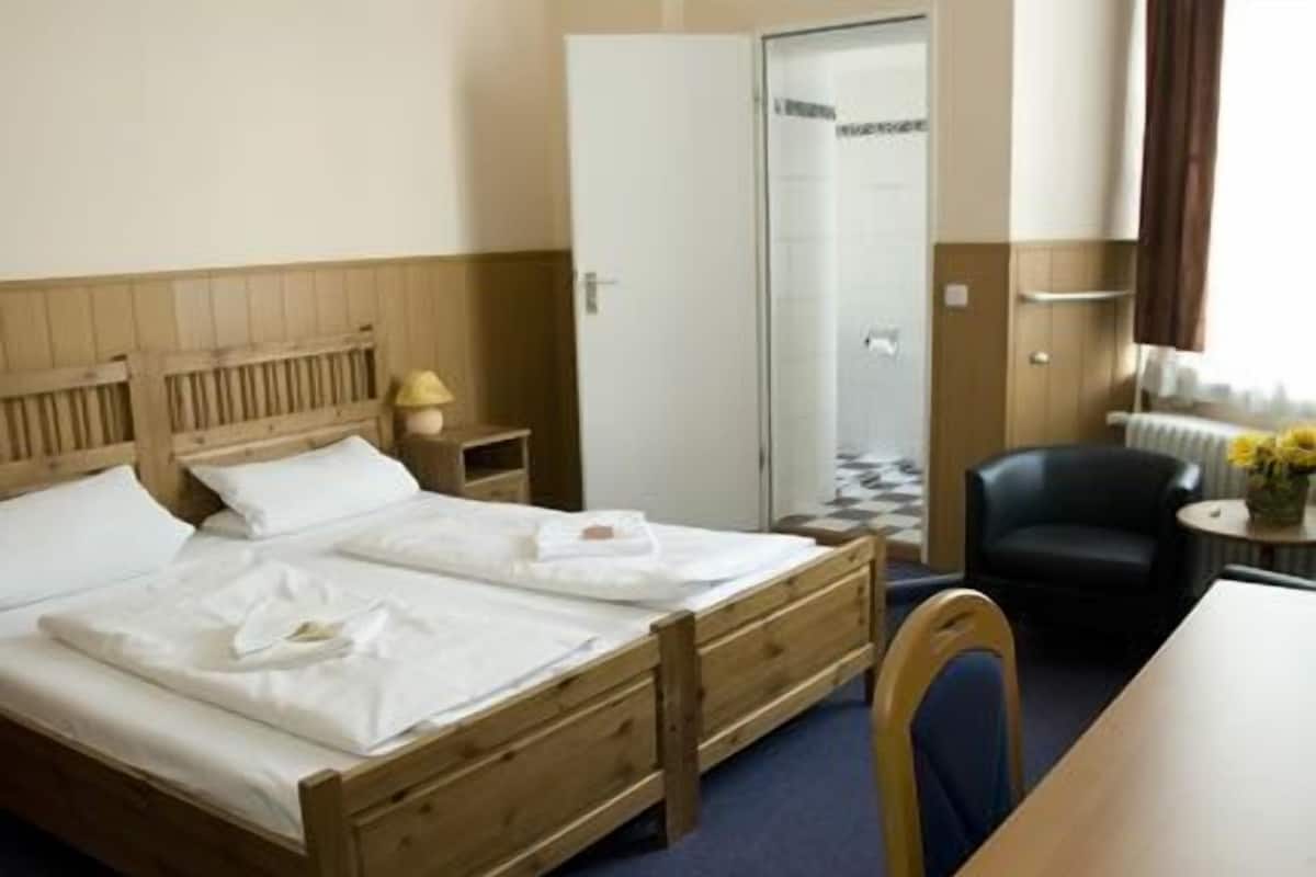 Une chambre d’hôtel avec un lit en bois, un bureau, une chaise et une armoire.