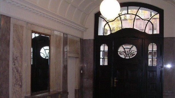 A dark wooden door with glass panels and a round light fixture above it. - Hotel Pension Rheingold (Berlin)