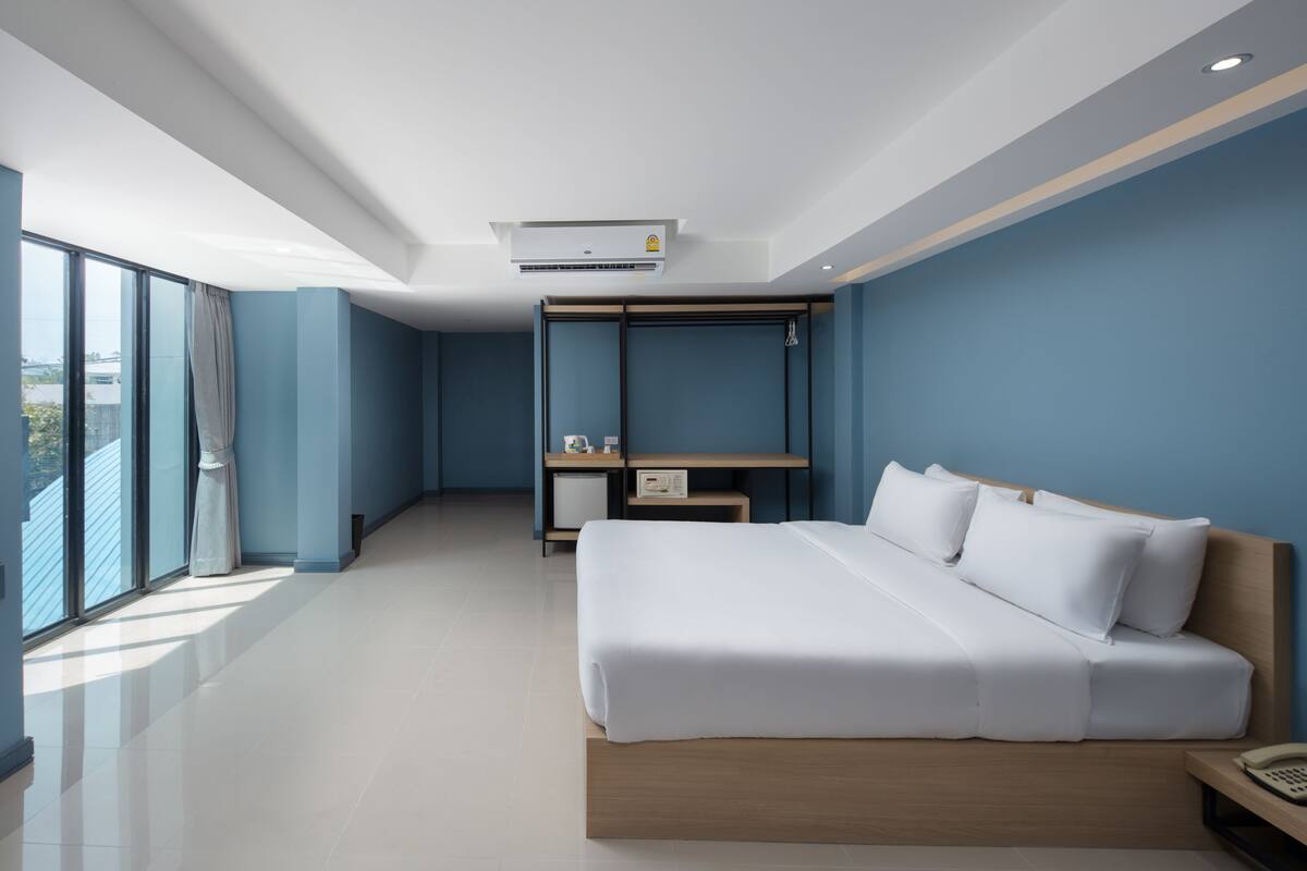 A modern hotel room with a large bed, a desk, and a wardrobe.
