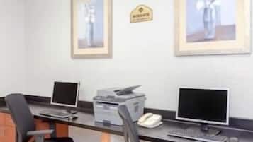 A modern office space with two desks, each equipped with a computer monitor, keyboard, and mouse. There are framed pictures on the wall, and a sign that reads "WINGATE."