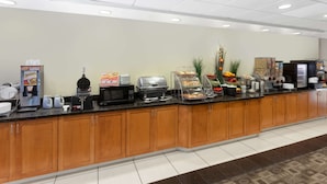 A breakfast bar with a coffee machine, toaster, and various food items. - Wingate by Wyndham Yuma (Yuma)