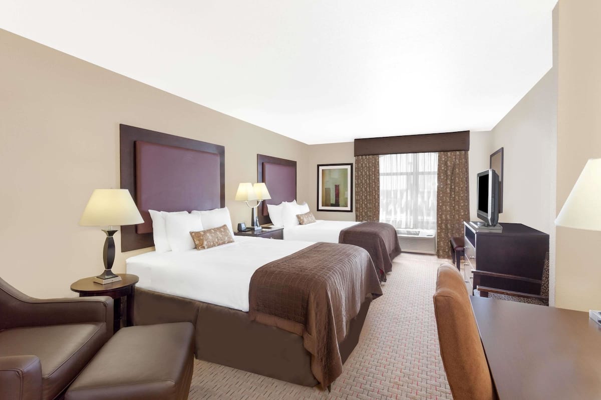 A hotel room with two beds, a TV, a desk, and a chair.