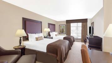 A hotel room with two beds, a TV, a desk, and a chair.