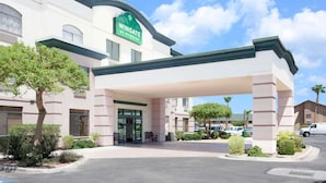 A Wingate by Wyndham hotel with a covered entrance, parking lot, and surrounding greenery. - Wingate by Wyndham Yuma (Yuma)