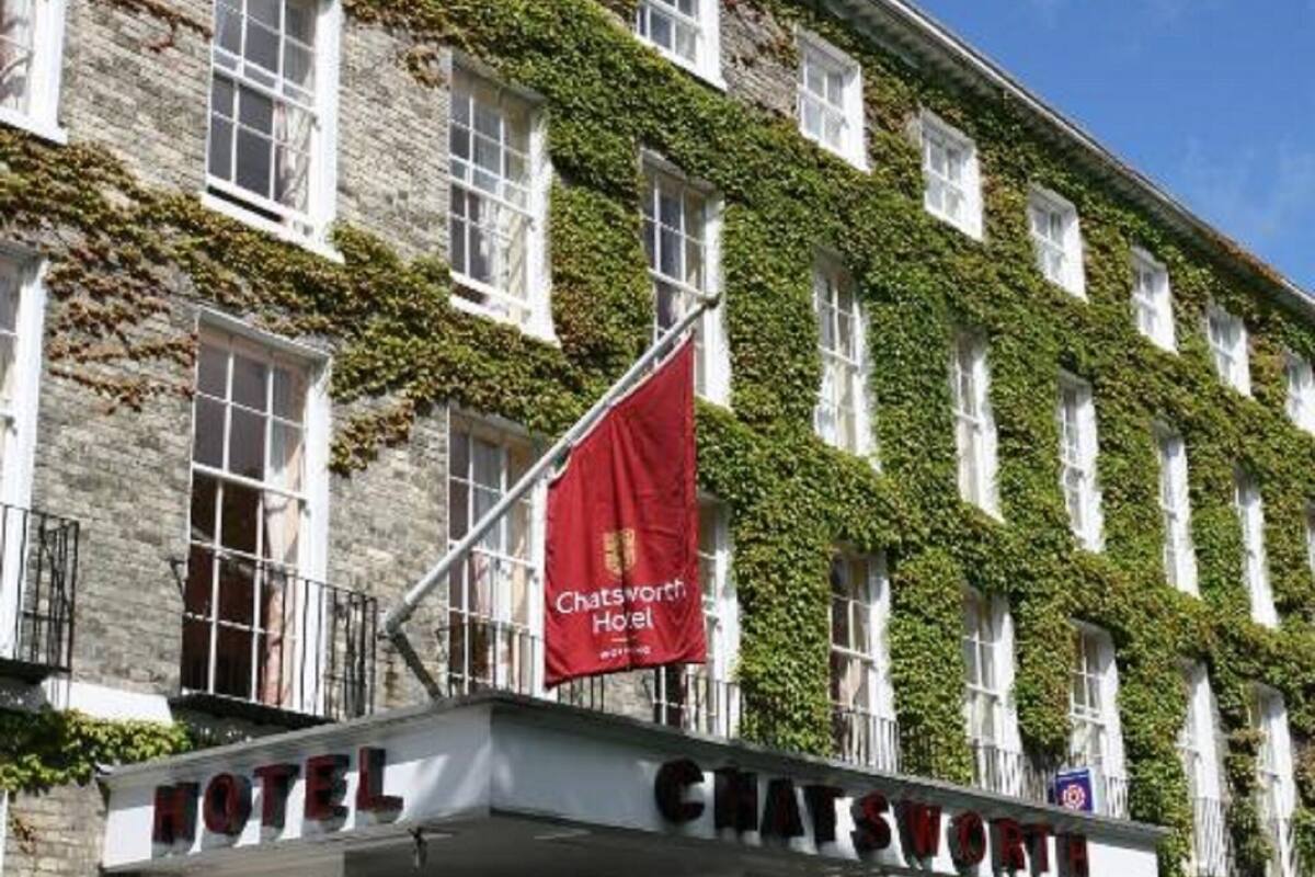 A hotel facade with a classic design, featuring a stone exterior and green ivy covering the upper part.