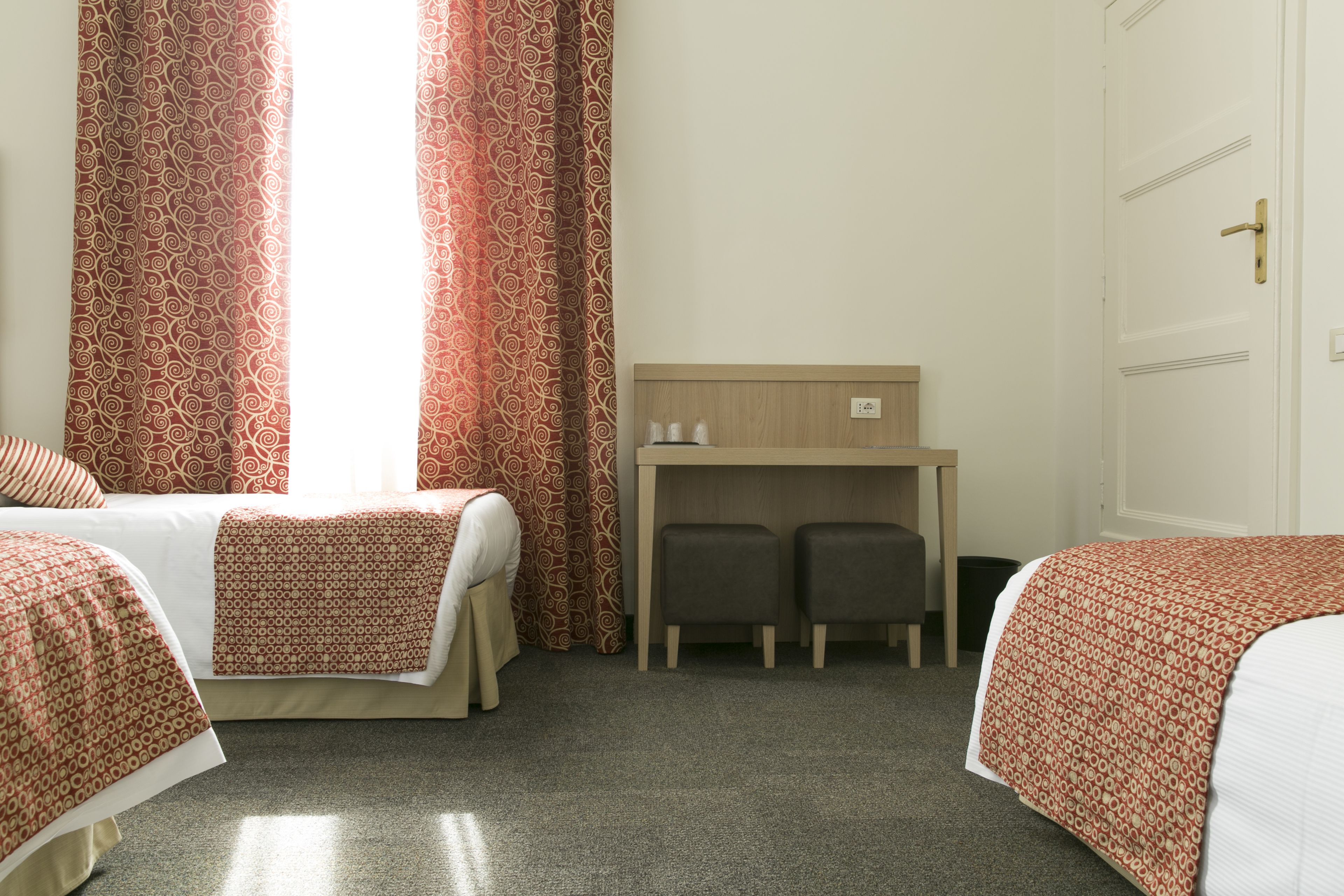 Habitación de hotel con dos camas, un escritorio pequeño y una puerta.