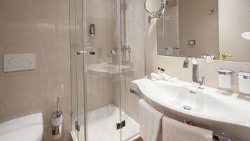 A modern bathroom with a glass-enclosed shower, a white sink, and a large mirror.