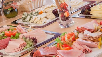 Una mesa con diversos alimentos, incluyendo carnes, quesos y frutas.