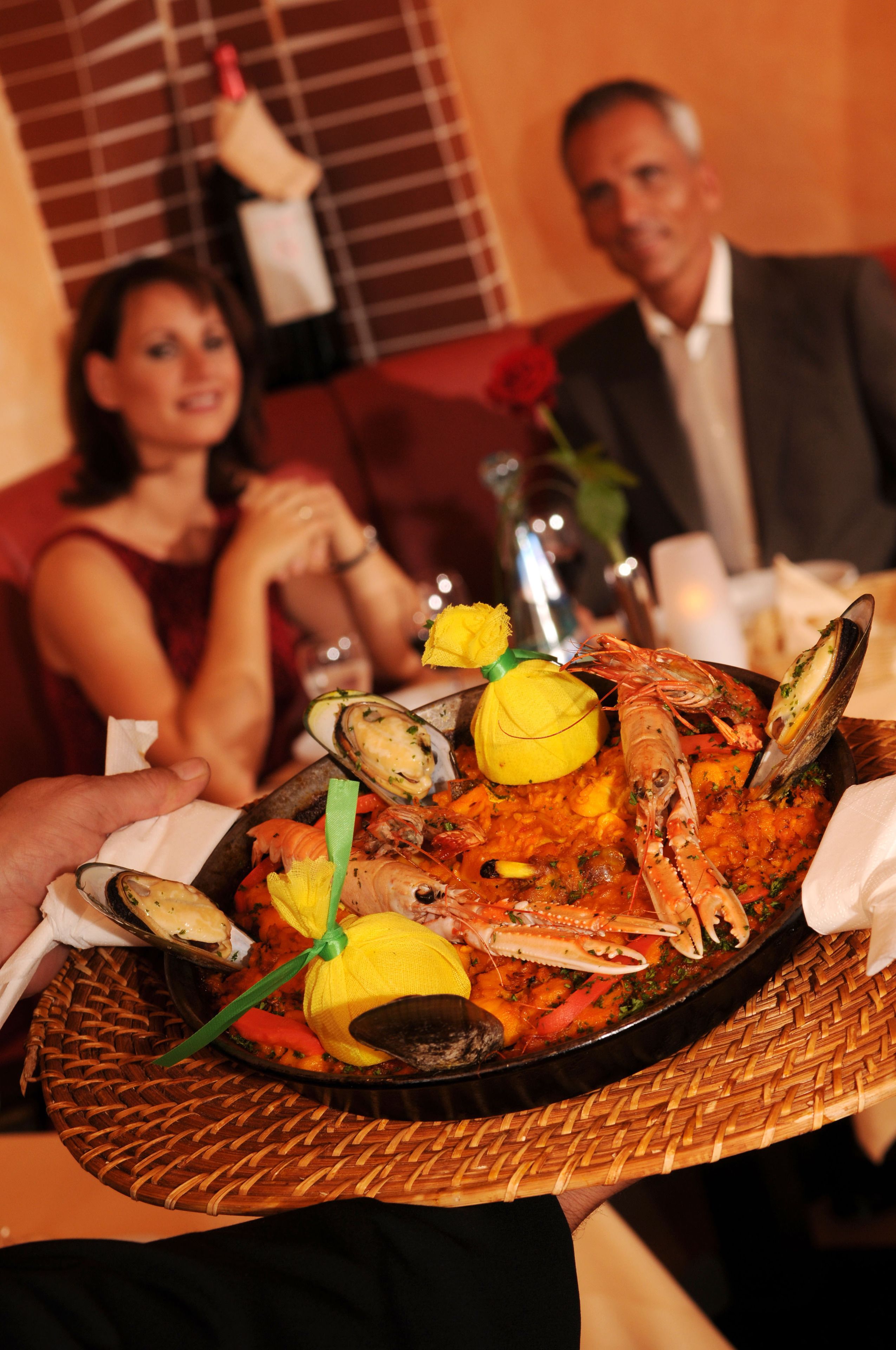 A person holding a seafood platter with mussels, shrimp, and lemon slices.
