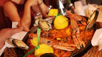 A person holding a seafood platter with mussels, shrimp, and lemon slices.
