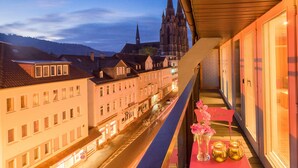 A balcony with a view of a city street, a church spire, and a row of buildings. - Hotel Marburger Hof (Marburg)