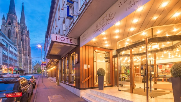 A hotel with a prominent 'HOTEL' sign, a welcoming entrance with glass doors, and a view of a historic building in the background. - Hotel Marburger Hof (Marburg)