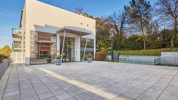 A modern building with a reception area, large windows, and a paved entrance.