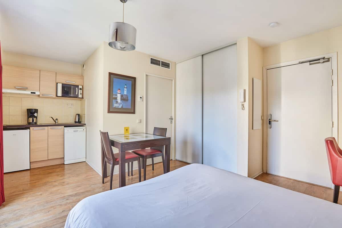 Ein Hotelzimmer mit einem Bett, einem Esstisch mit Stühlen, einer Mikrowelle, einer Kaffeemaschine und einer Schiebetür.