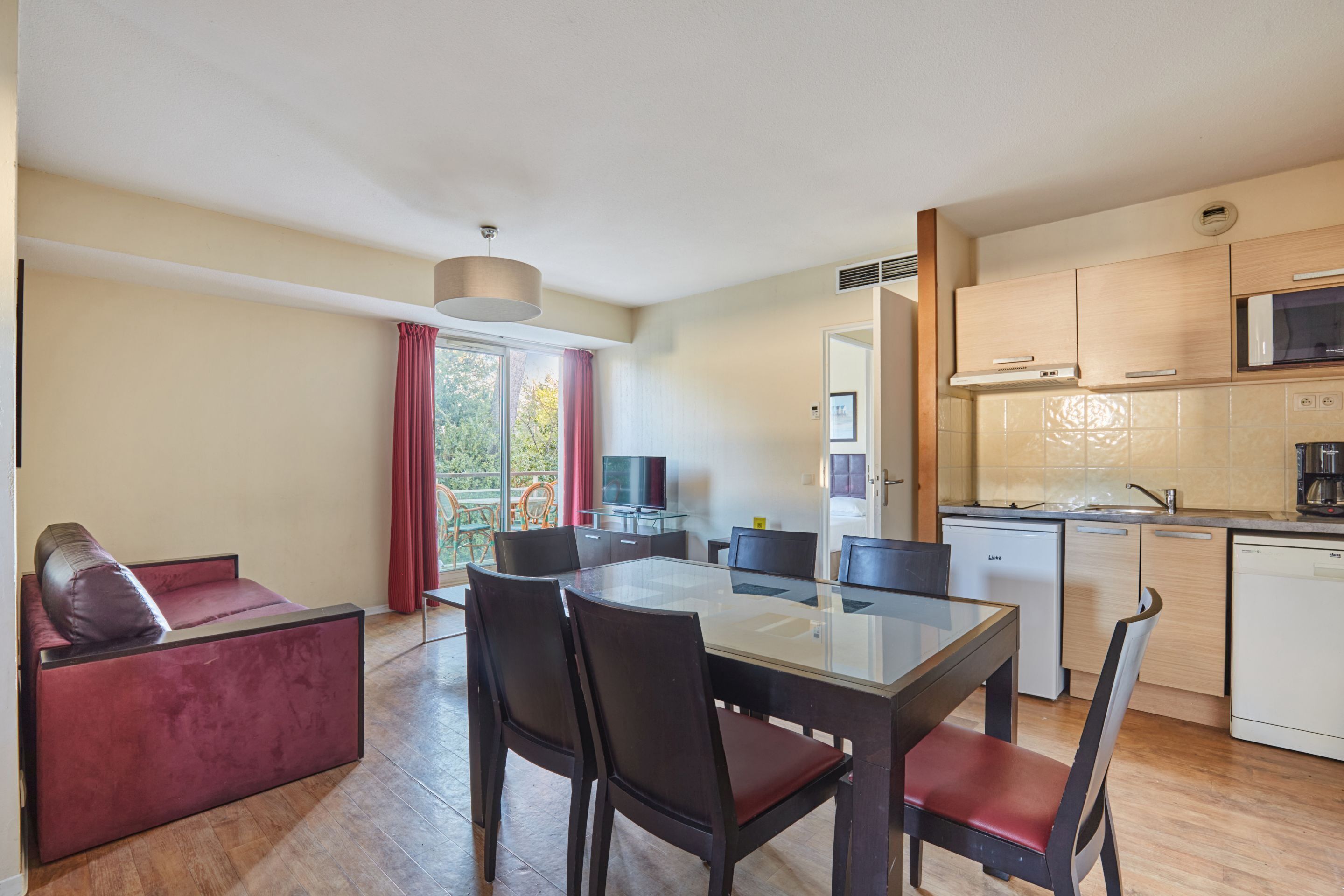 A modern kitchen with a dining area, a sofa, and a television.