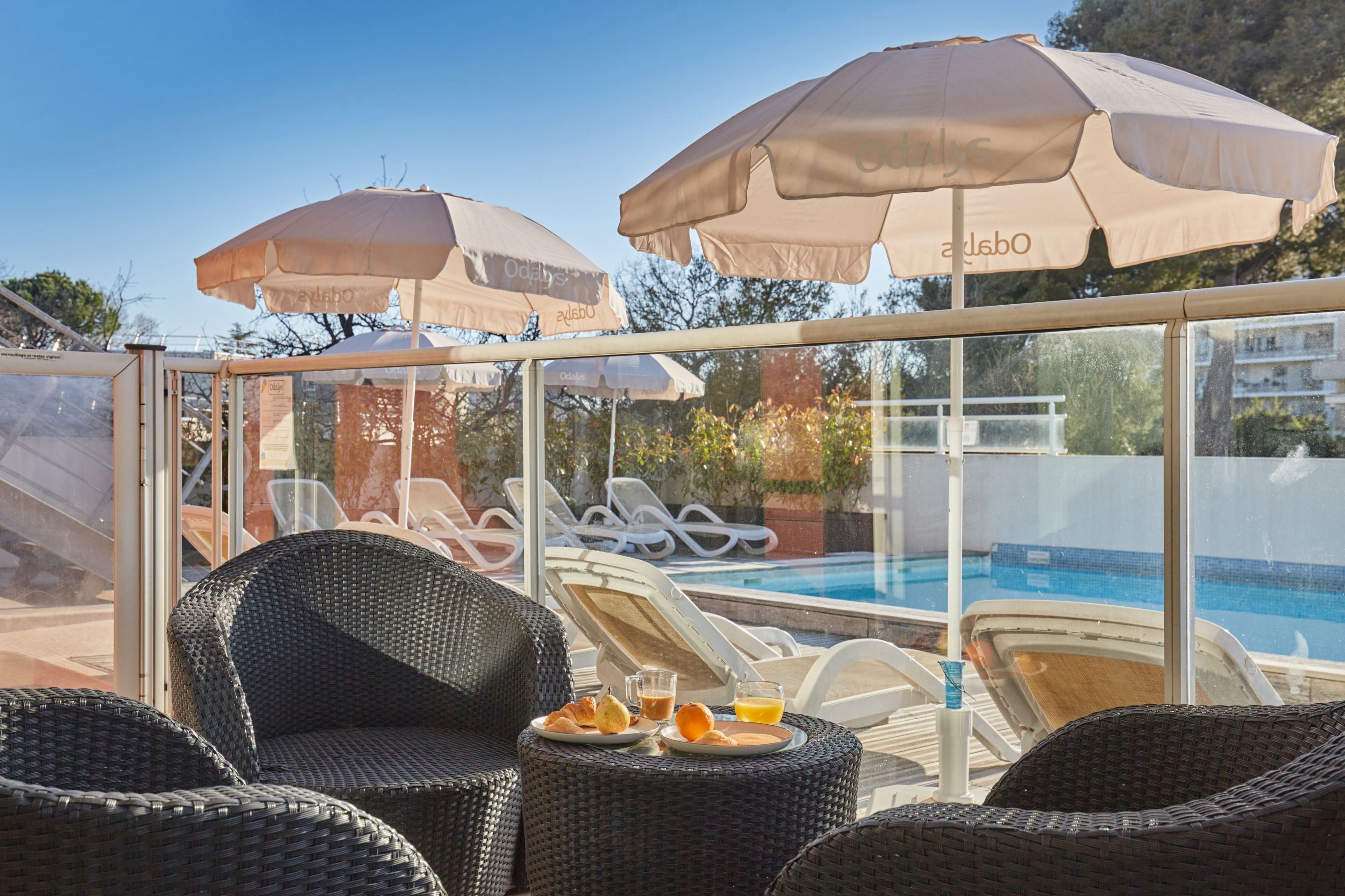 Een zwembadgedeelte met ligbedden, parasols en een tafel met ontbijtartikelen.