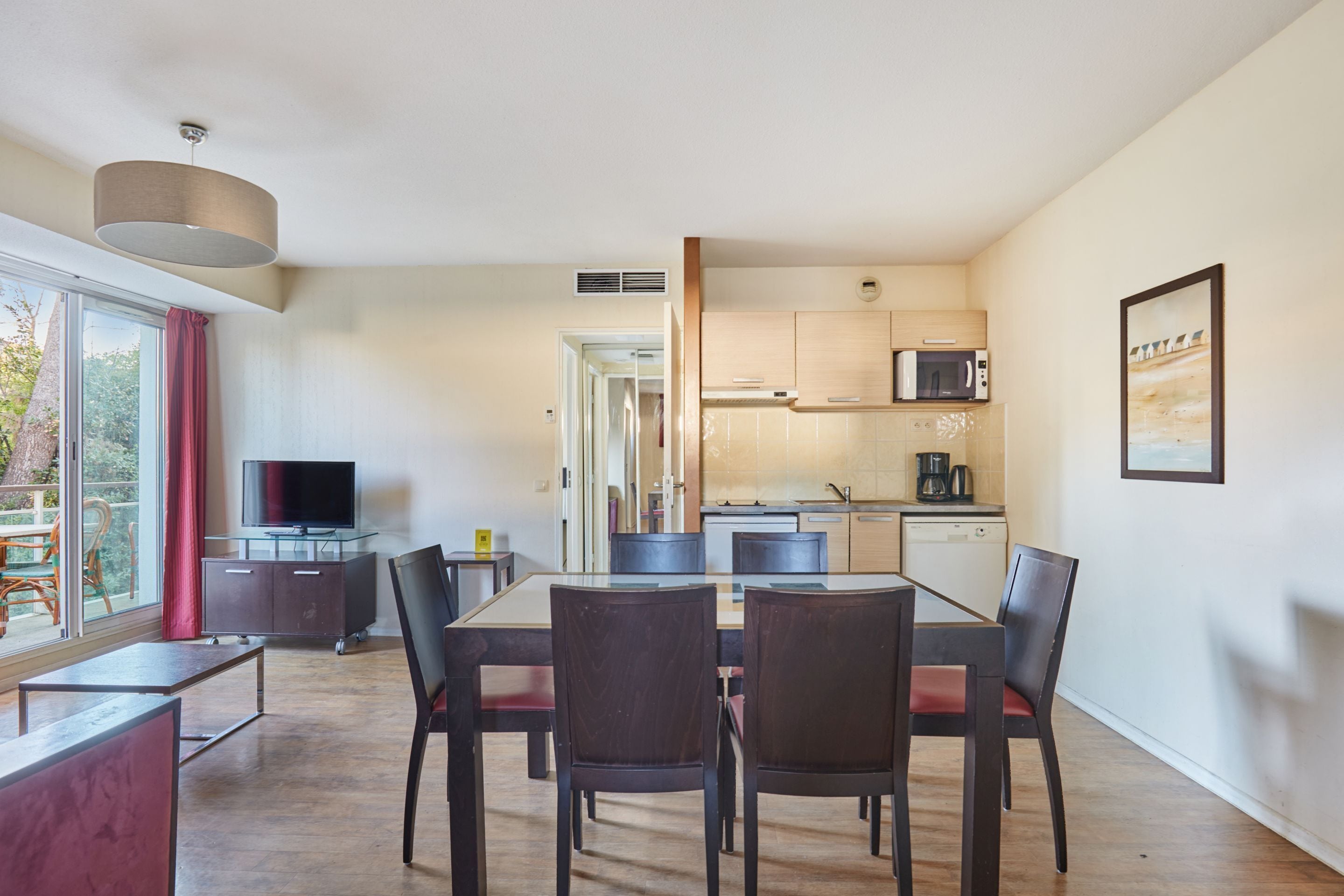 A modern living space with a dining area, kitchen, and a TV.