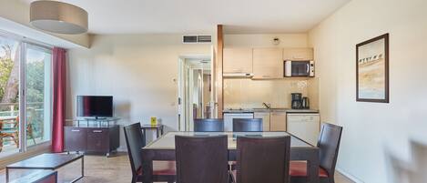 A modern living space with a dining area, kitchen, and a TV.