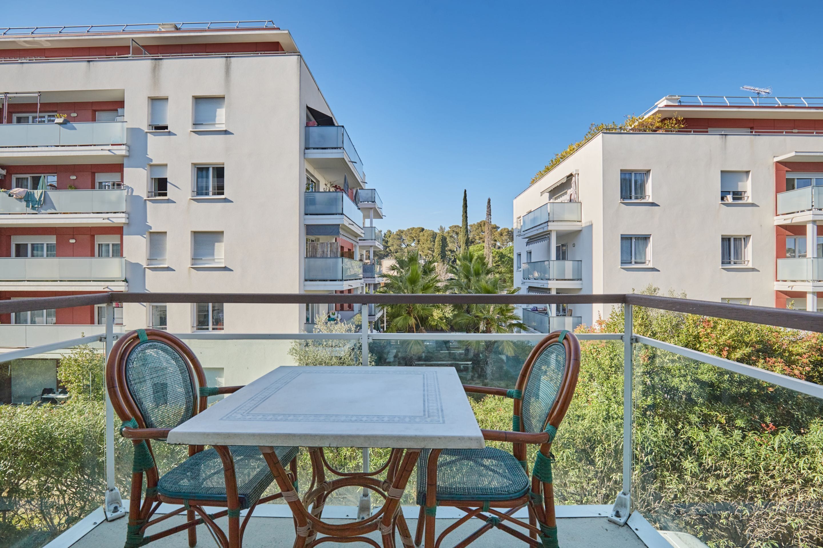A balcony with a table and chairs, overlooking a residential area with apartment buildings.