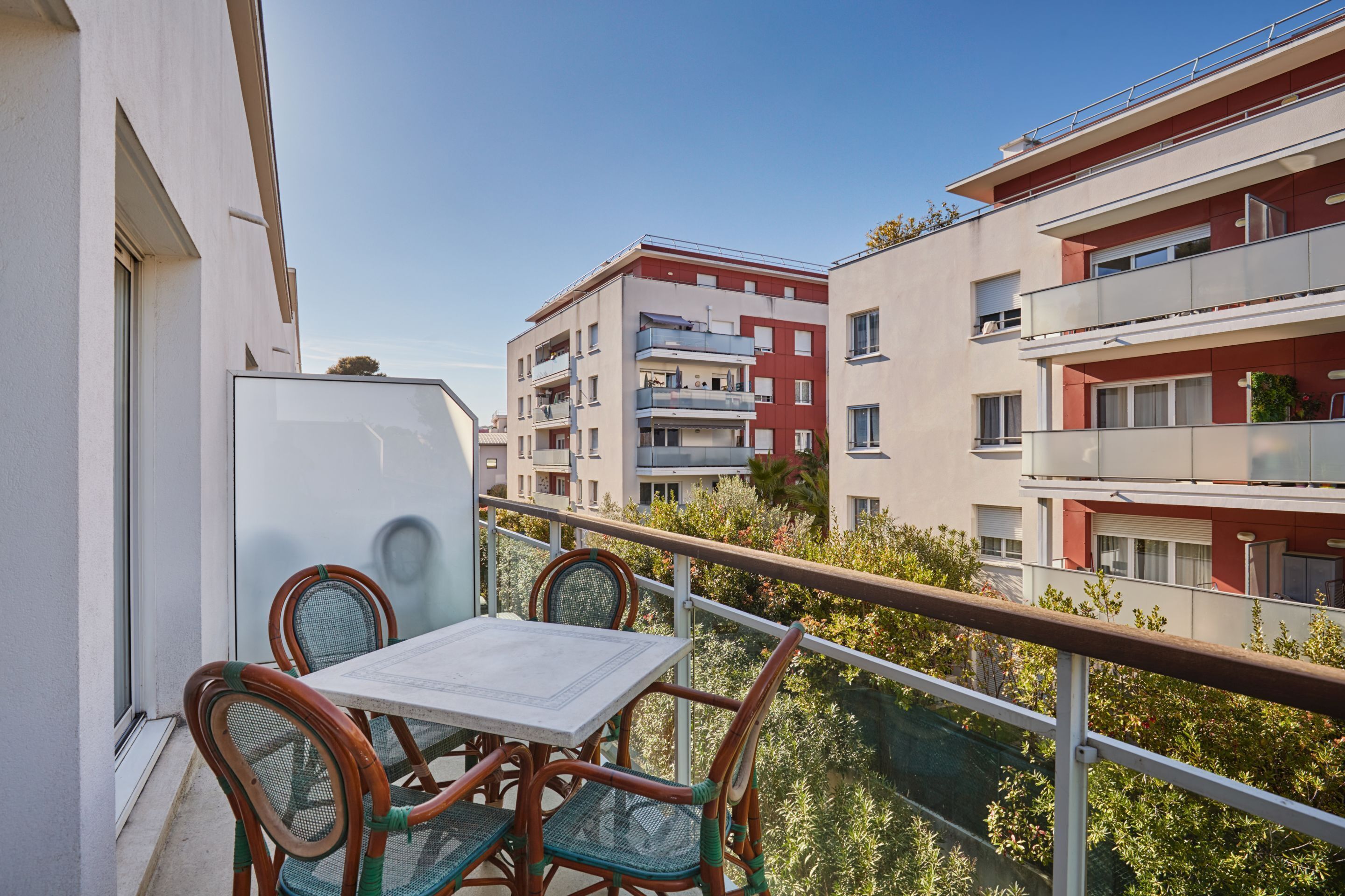 Un balcon avec une table et des chaises, donnant sur un quartier résidentiel composé d  ’immeubles à plusieurs étages.