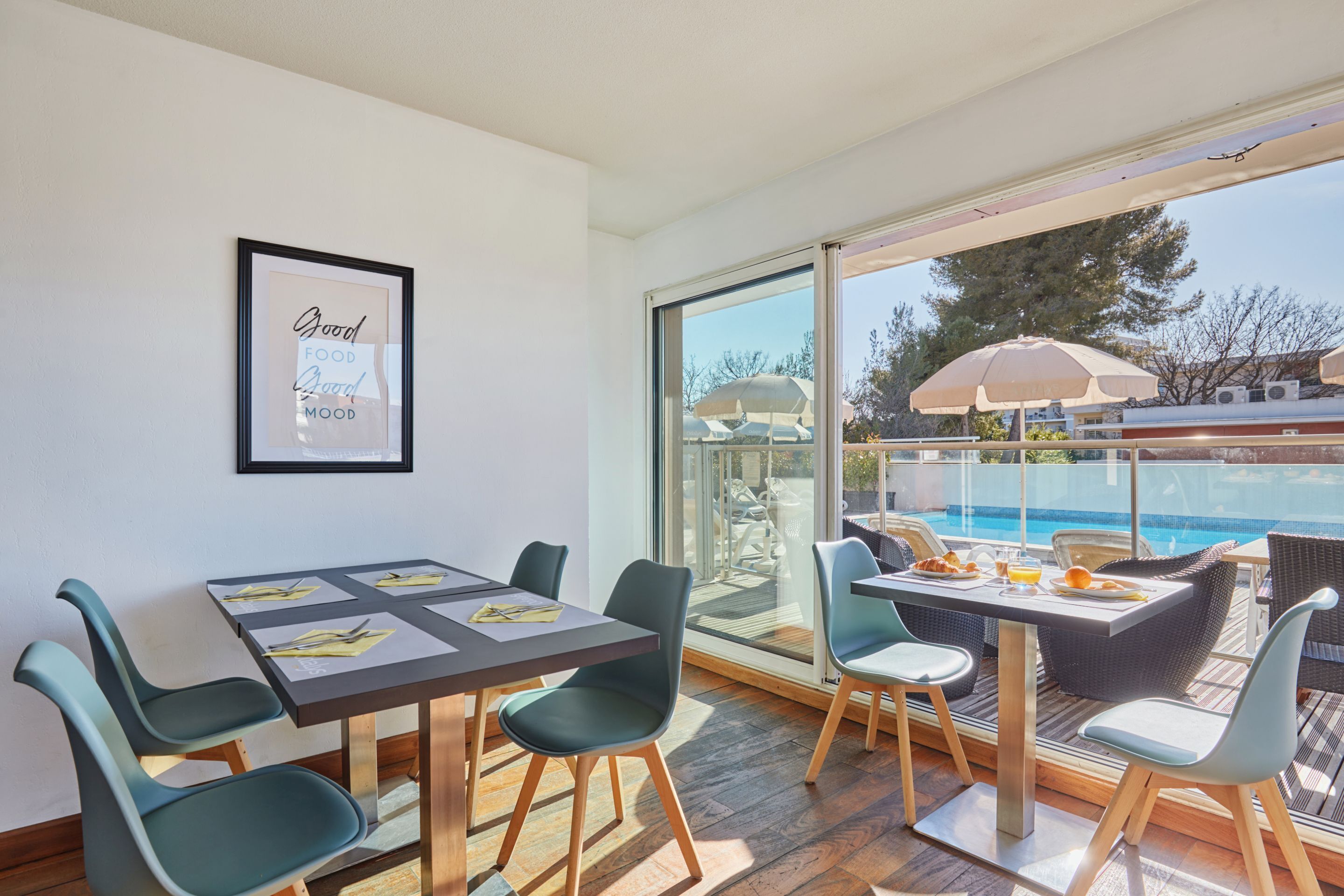 Un comedor con una mesa y sillas, una cita enmarcada en la pared y vistas a una piscina.