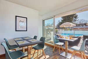 Un comedor con una mesa y sillas, una cita enmarcada en la pared y vistas a una piscina.