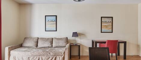 Une chambre moderne avec un canapé, une petite table, une lampe et un bureau avec une chaise.