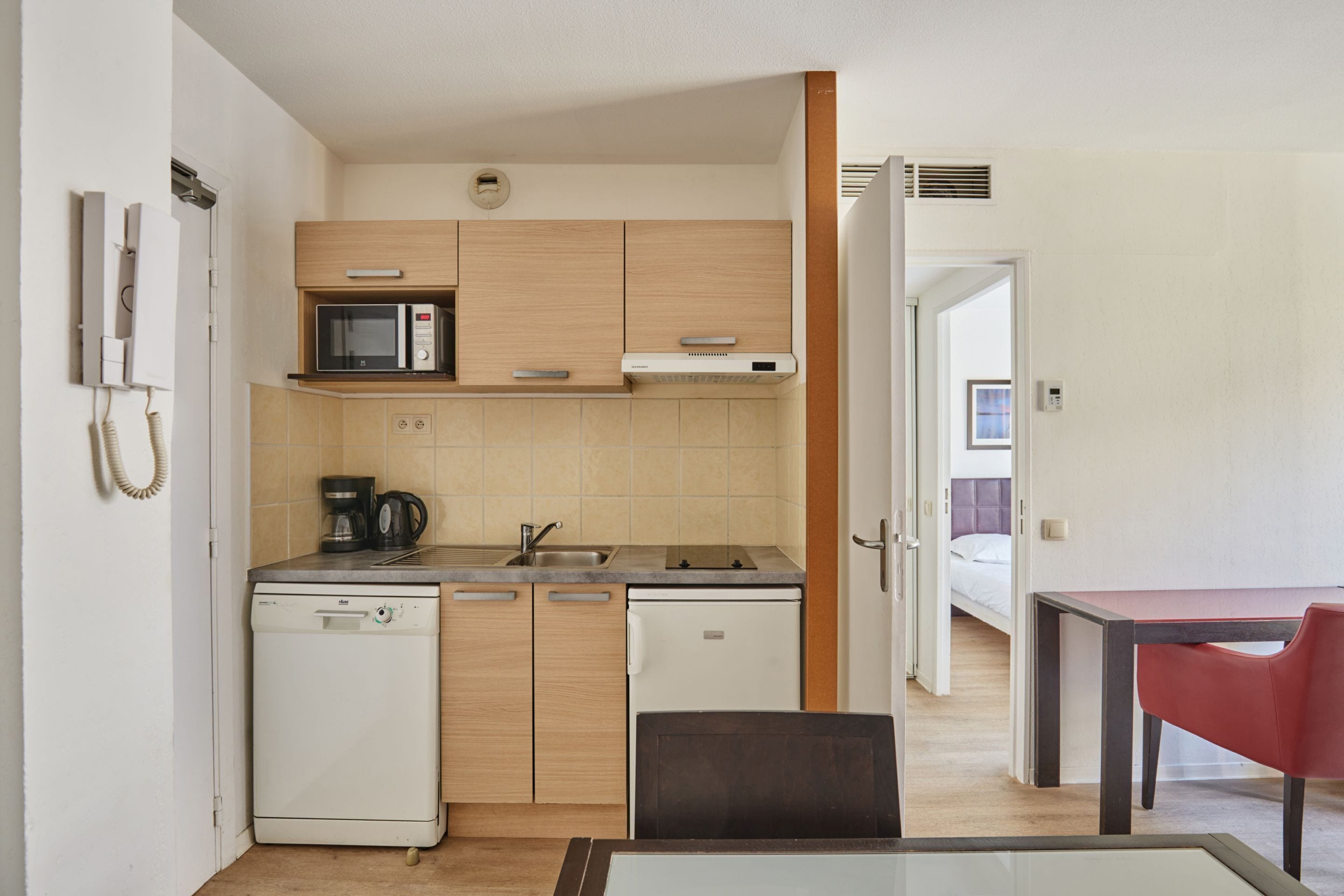 Una cocina compacta equipada con microondas, cafetera y lavavajillas.