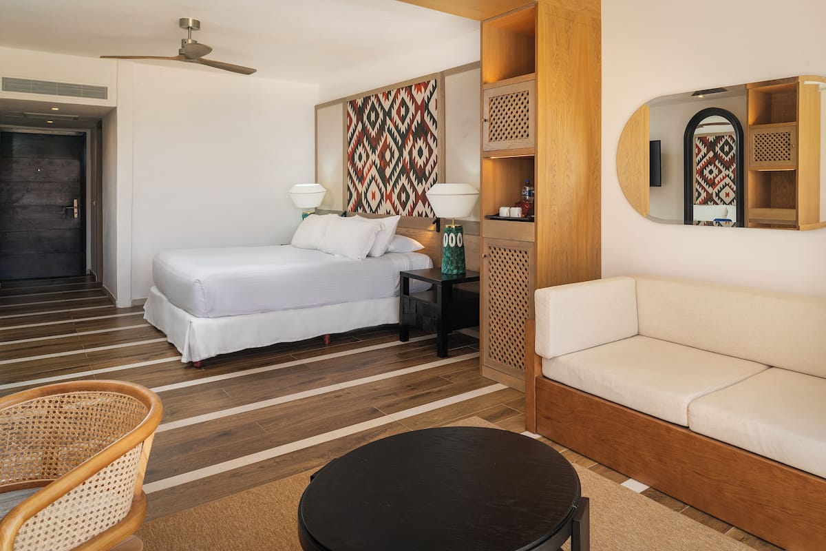 Une chambre d’hôtel équipée d’un lit, d’un canapé, d’une table à manger et d’un ventilateur de plafond.