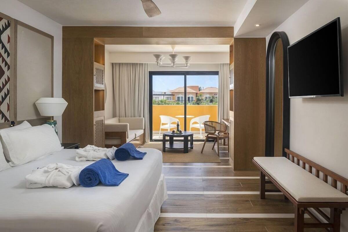Une chambre d’hôtel comprenant un lit, une banquette, une télévision, un balcon avec vue et un coin repas.