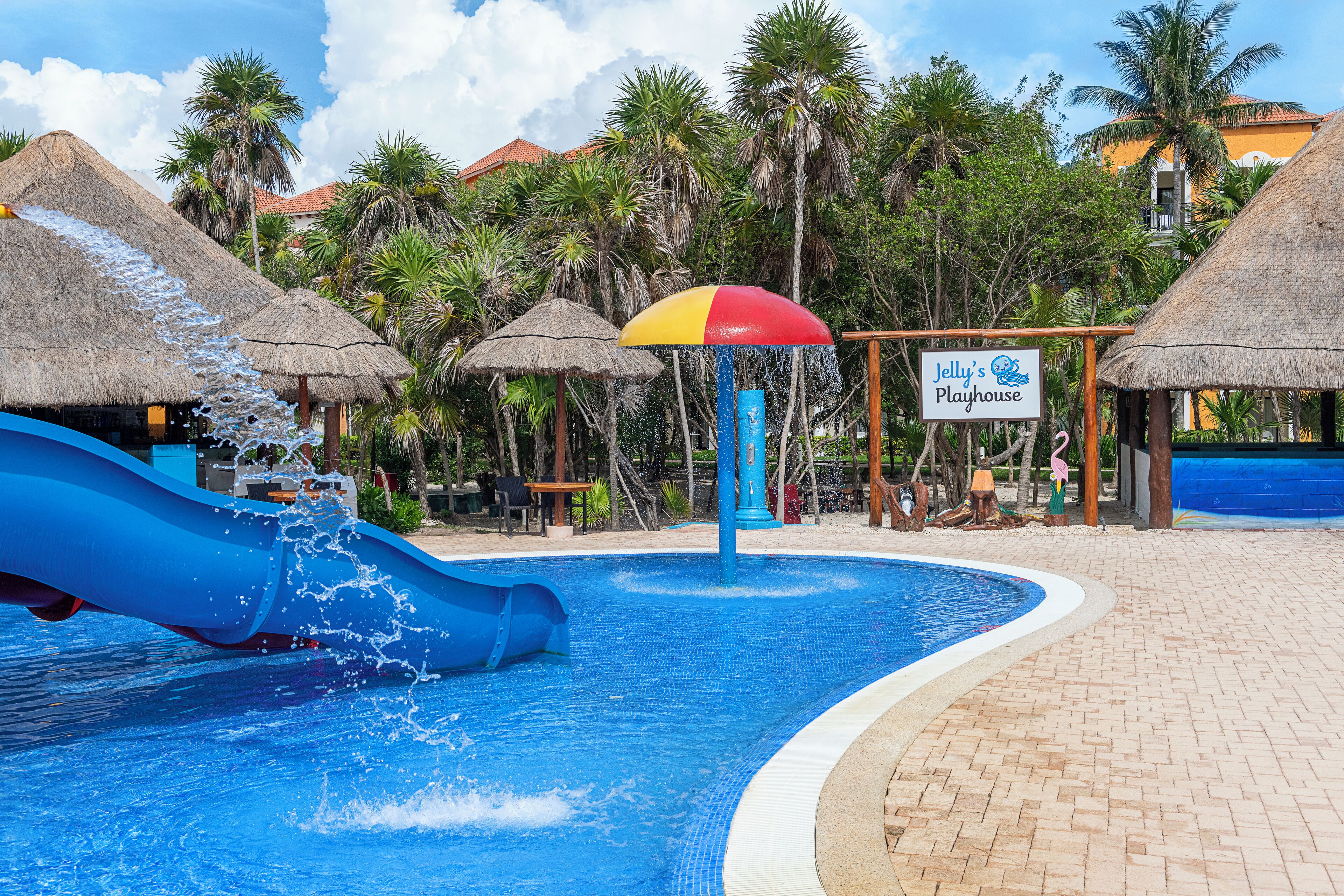 A water park area with a blue slide, a water fountain, and a sign for Jelly's Playhouse.