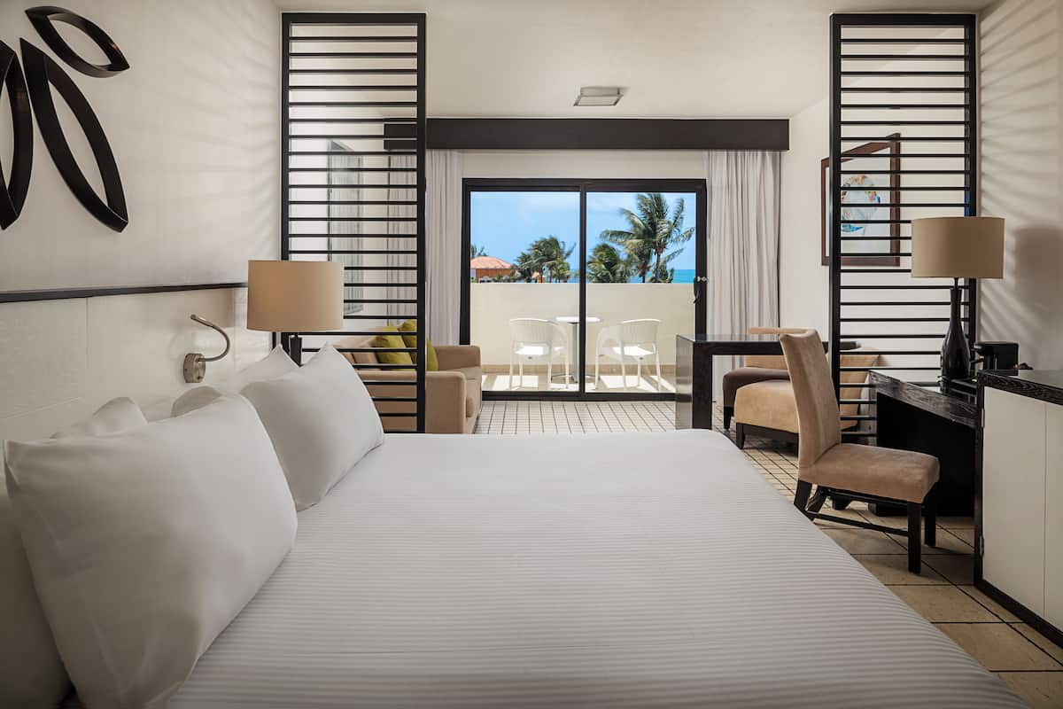 Une chambre d’hôtel avec un grand lit, un bureau, une chaise et un balcon avec vue.