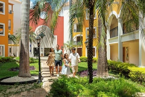A courtyard with a pathway, palm trees, and buildings with balconies.