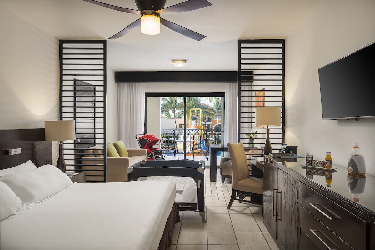 Une chambre d’hôtel équipée d’un lit, d’un bureau, de chaises, d’une télévision et d’un balcon avec vue.