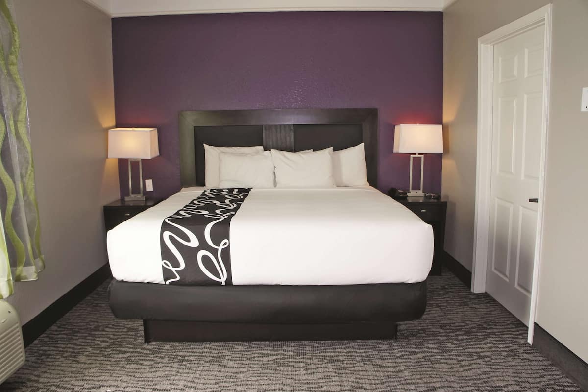 A hotel room with a large bed, two bedside tables, and a door.
