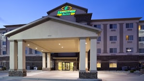 Een hotelentree met een overdekte doorgang, een bakstenen gevel en een bord met de tekst Expressway Suites.