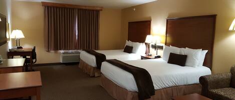A hotel room with two beds, a desk, a chair, and a couch.