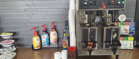 Una cafetera con panel de control, espumador de leche y molinillo. Hay botellas de leche condensada y leche en la encimera.