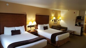 Een hotelkamer met twee bedden, een bank, een bureau en een magnetron.
