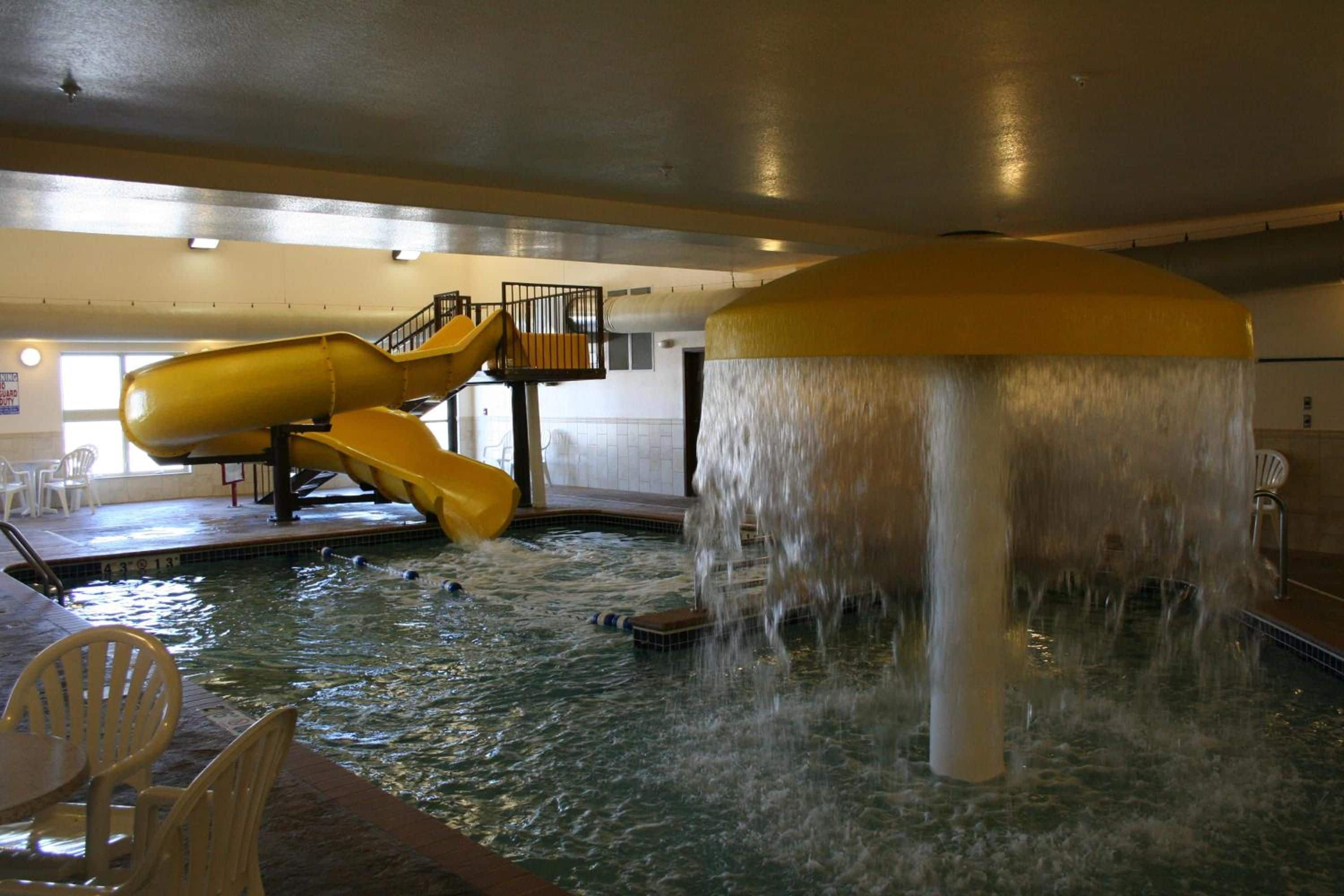An indoor water park with a slide and a water fountain.
