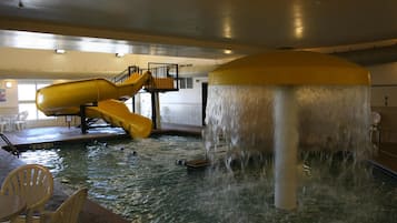 Un parque acuático interior con tobogán y fuente de agua.