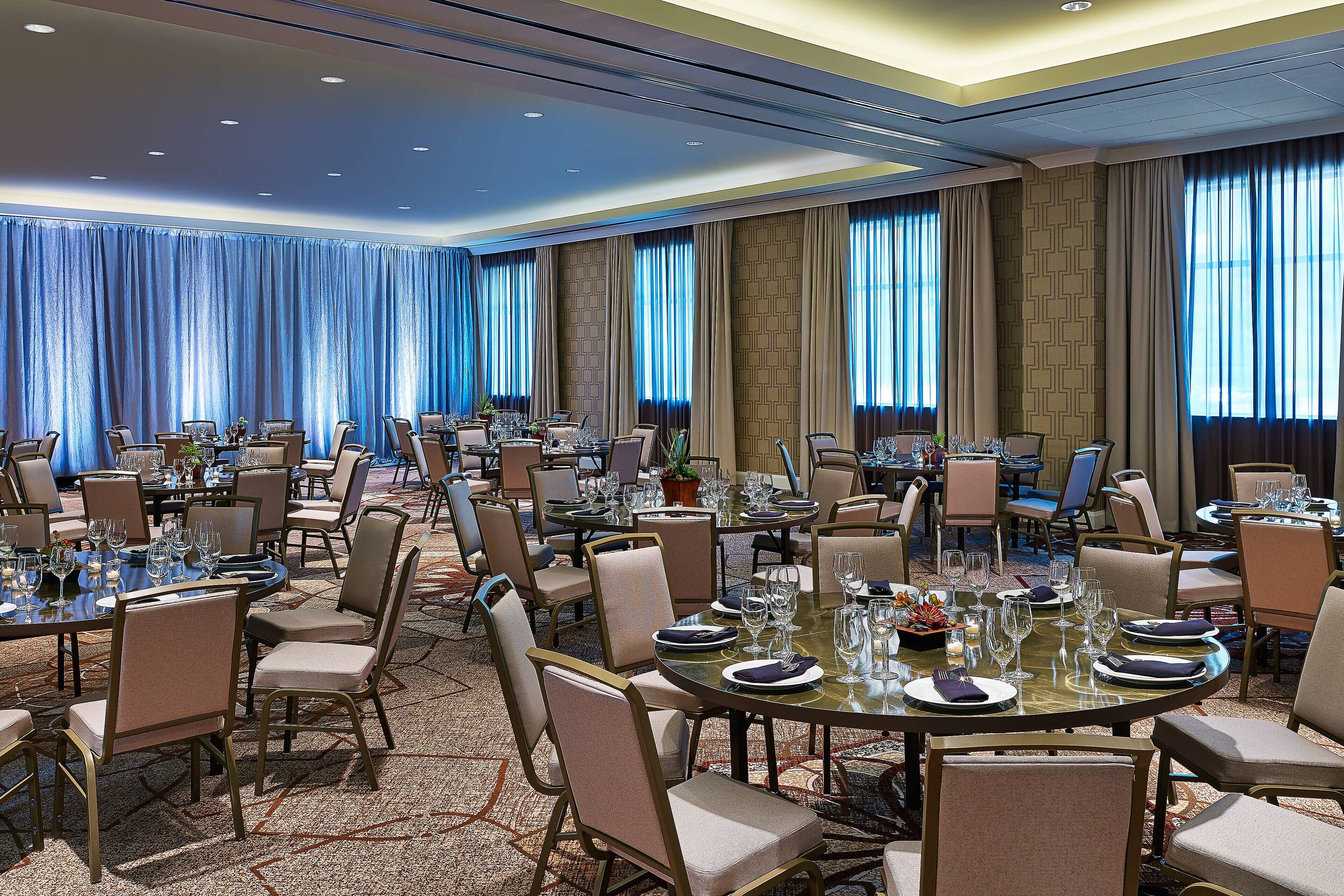 A conference room with multiple tables set for dining, equipped with chairs and dining essentials.