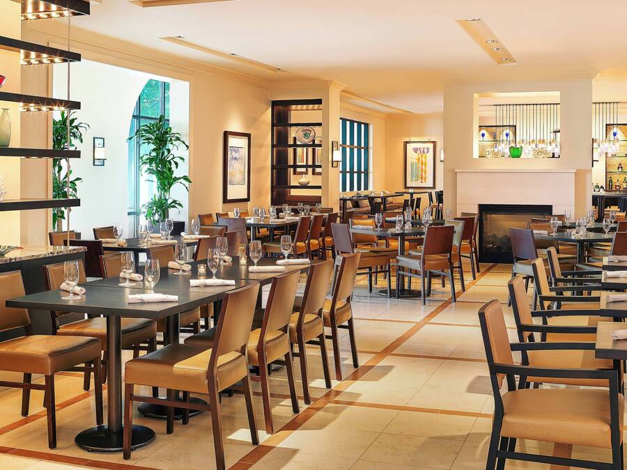 A spacious dining area with multiple tables and chairs, a fireplace, and shelves with decorative items.